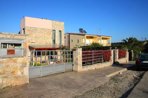 a fence in front of a house with a building at Comfy flat with Garden near the Beach in Theológos