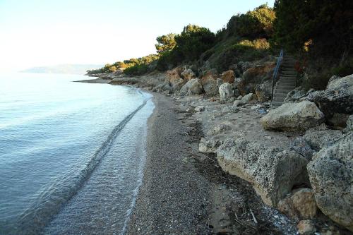 a beach with rocks and stairs next to the water at Comfy flat with Garden near the Beach in Theológos