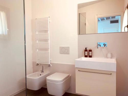 ein Badezimmer mit einem WC, einem Waschbecken und einem Spiegel in der Unterkunft Villa Tanaquilla in Baratti