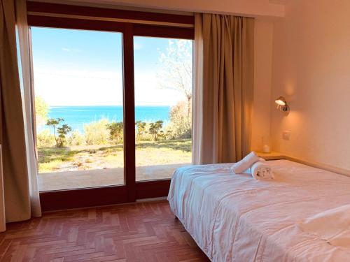 a bedroom with a bed and a large window at Villa Tanaquilla in Baratti