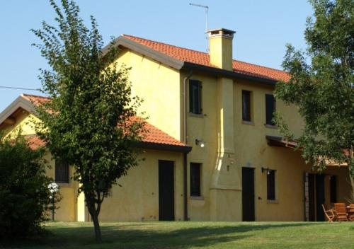 Una gran casa amarilla con un árbol delante. en Agriturismo Zennare, en Chioggia