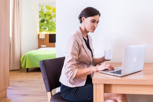 a woman sitting at a table with a laptop computer at INhouse - Wohnen auf Zeit in Ingolstadt