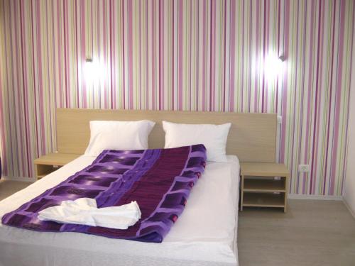 1 dormitorio con 1 cama grande con sábanas moradas en Vila Malva, en Eforie Nord