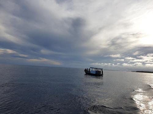 a boat in the water under a cloudy sky at Finimas Residence in Thimarafushi