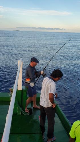 two men fishing on a boat in the water at Finimas Residence in Thimarafushi