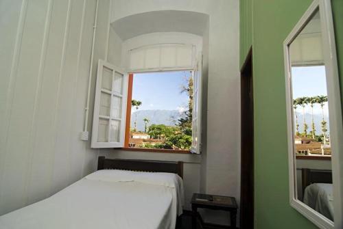 1 dormitorio con cama blanca y ventana en Nhundiaquara Hotel e Restaurante, en Morretes