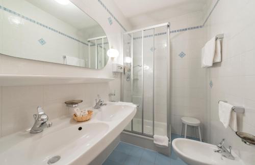 biała łazienka z umywalką i prysznicem w obiekcie Kristallhotel Corona-Krone w mieście San Vigilio di Marebbe