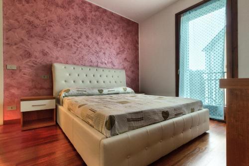 ein Schlafzimmer mit einem Bett und einer rosa Wand in der Unterkunft Residence San Miguel (4) in Vicenza