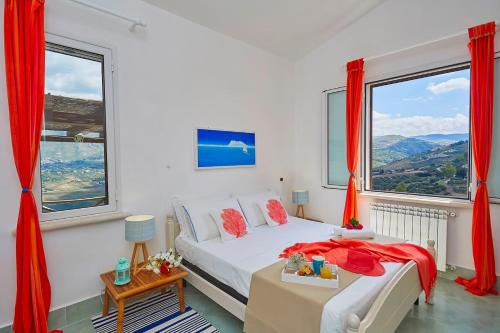 a bedroom with a bed and windows with red curtains at Villa Delfino - Scopello-Villas in Scopello