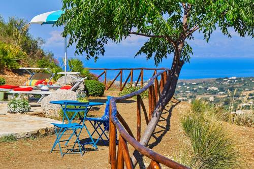 a table and chairs with the ocean in the background at Villa Delfino - Scopello-Villas in Scopello