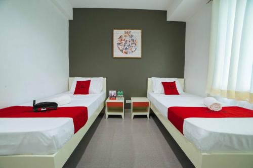 2 Betten in einem Zimmer mit roter und weißer Bettwäsche in der Unterkunft RedDoorz Plus @ Roxas Street Davao in Davao City