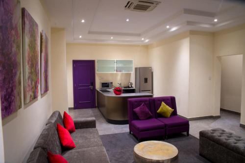 Una sala de estar con un sofá morado y una cocina. en The Francis Hotel, en Abuja