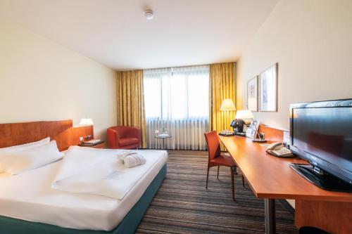 a hotel room with a bed and a desk at Mercure Hotel am Messeplatz Offenburg in Offenburg