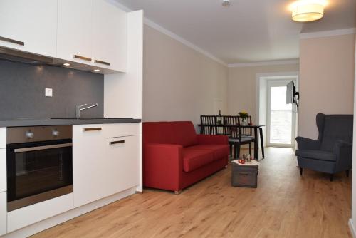 eine Küche und ein Wohnzimmer mit einem roten Sofa in der Unterkunft Apartment Torhaus Schloss Wocklum in Balve