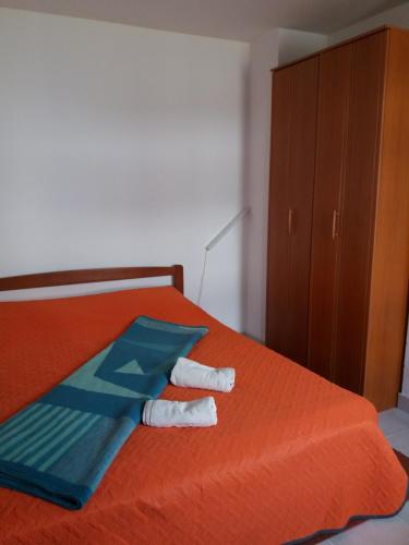 a bedroom with an orange bed with towels on it at APARTMAN KOREN in Malinska
