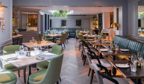 ロンドンにある11 Cadogan Gardens, The Apartments and The Chelsea Townhouse by Iconic Luxury Hotelsの木製テーブルと緑の椅子が備わるレストラン