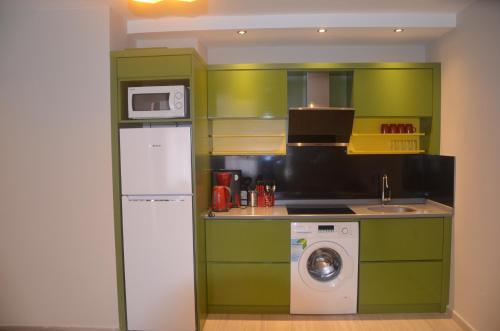 a kitchen with green cabinets and a washing machine at Twin Apart Hotel in Alanya
