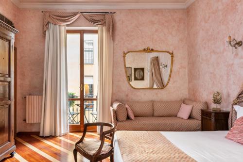 a bedroom with a bed and a couch and a mirror at Hotel Sanpi Milano in Milan