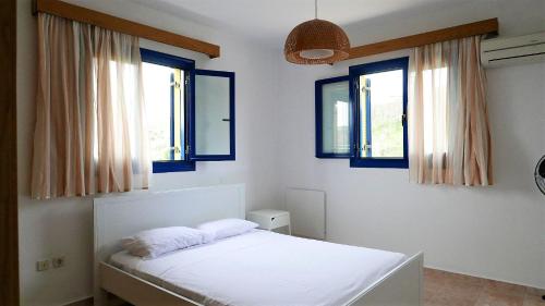 a bedroom with a white bed and two windows at Electra Village House in Apolakkiá