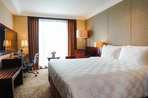 a hotel room with a large bed and a desk at Swiss-Belhotel Serpong in Serpong