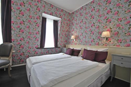 a bedroom with two beds and floral wallpaper at Hotel Domspitzen in Cologne