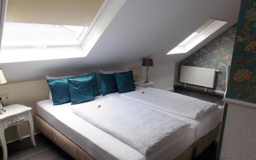 a bedroom with a large bed with blue pillows at Hotel Domspitzen in Cologne
