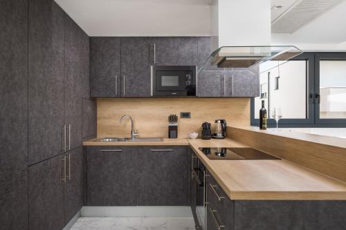Una cocina con armarios de madera, fregadero y microondas. en Luxury Apartments Baotić, en Trogir