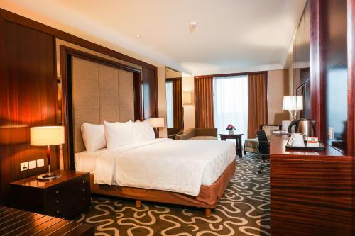 a hotel room with a bed and a living room at Swiss-Belhotel Serpong in Serpong