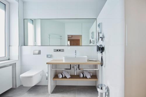 Baño blanco con lavabo y aseo en Hotel Rose en Rüdesheim am Rhein