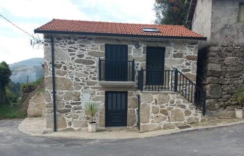 a stone house with a black door and a balcony at Vivenda da Eva in Arcos de Valdevez