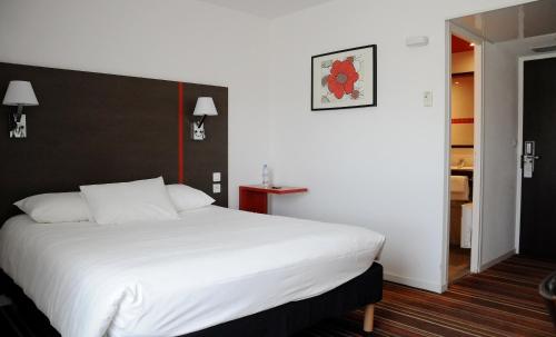 a bedroom with a large white bed with a black headboard at ibis Styles Segre in Segré