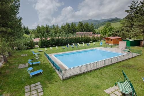 a swimming pool in a yard with chairs and a house at Hotel Iris in Pescasseroli
