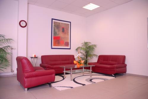 una sala de estar con 2 sillas rojas y una mesa. en Hotel Leipziger Land en Geithain