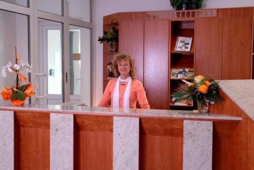 a woman standing behind a counter in a room at Hotel Leipziger Land in Geithain