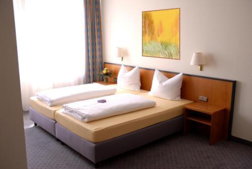 a hotel room with two beds with white pillows at Hotel Leipziger Land in Geithain