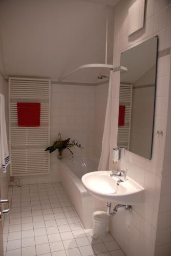 Hotel Leipziger Land في Geithain: حمام أبيض مع حوض وحوض ومغسلة