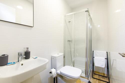 La salle de bains blanche est pourvue d'une douche et de toilettes. dans l'établissement Armijorooms, à Nerja