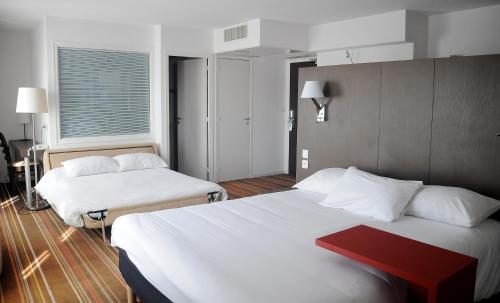 a hotel room with two beds and a red table at ibis Styles Segre in Segré