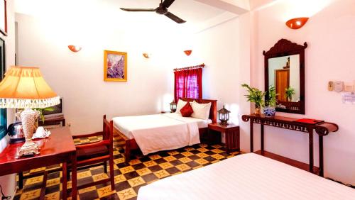 a bedroom with two beds and a desk and a mirror at Villa Wat Damnak in Siem Reap
