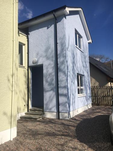 a blue house with a door in a yard at Fort William Studios in Fort William