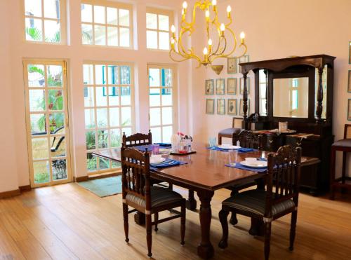 a dining room with a table with chairs and a chandelier at Mango Tree Courtyard Dehradun in Dehradun