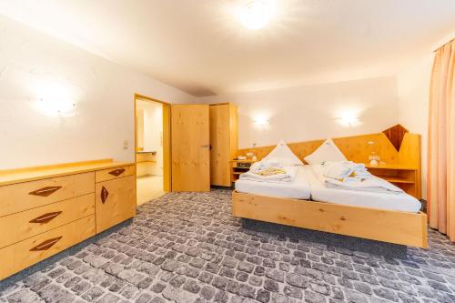 a bedroom with a bed and a dresser in it at Hotel Alpenhof in Bad Wörishofen