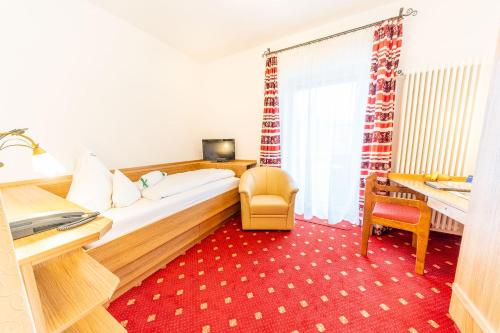 a hotel room with a bed and a chair and a desk at Hotel Alpenhof in Bad Wörishofen