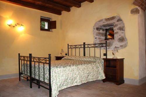 Schlafzimmer mit einem schwarzen Bett und einem Spiegel in der Unterkunft Agriturismo I Chiosi in Comano