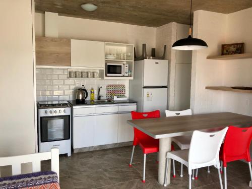 cocina con mesa de madera y sillas rojas en Las Olas Aparts, en La Paloma