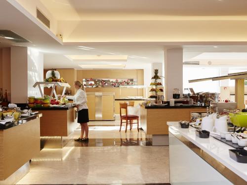 a woman standing at a counter in a kitchen at Lindos Mare, Seaside Hotel in Líndos