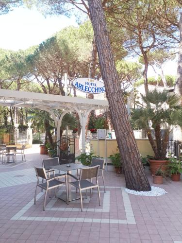 a patio with a table and chairs and trees at Hotel Arlecchino in Milano Marittima