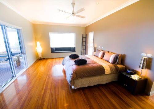 a bedroom with a large bed and a wooden floor at White House Ocean View Spa Villa in Burnt Pine