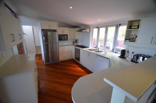 a kitchen with white cabinets and a wooden floor at White House Ocean View Spa Villa in Burnt Pine