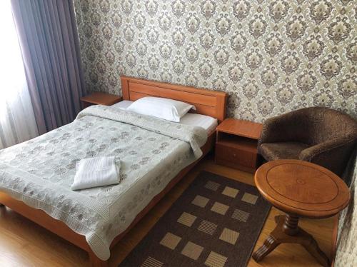 a small bedroom with a bed and a chair at Гостиница "Алтын Орда" in Astana